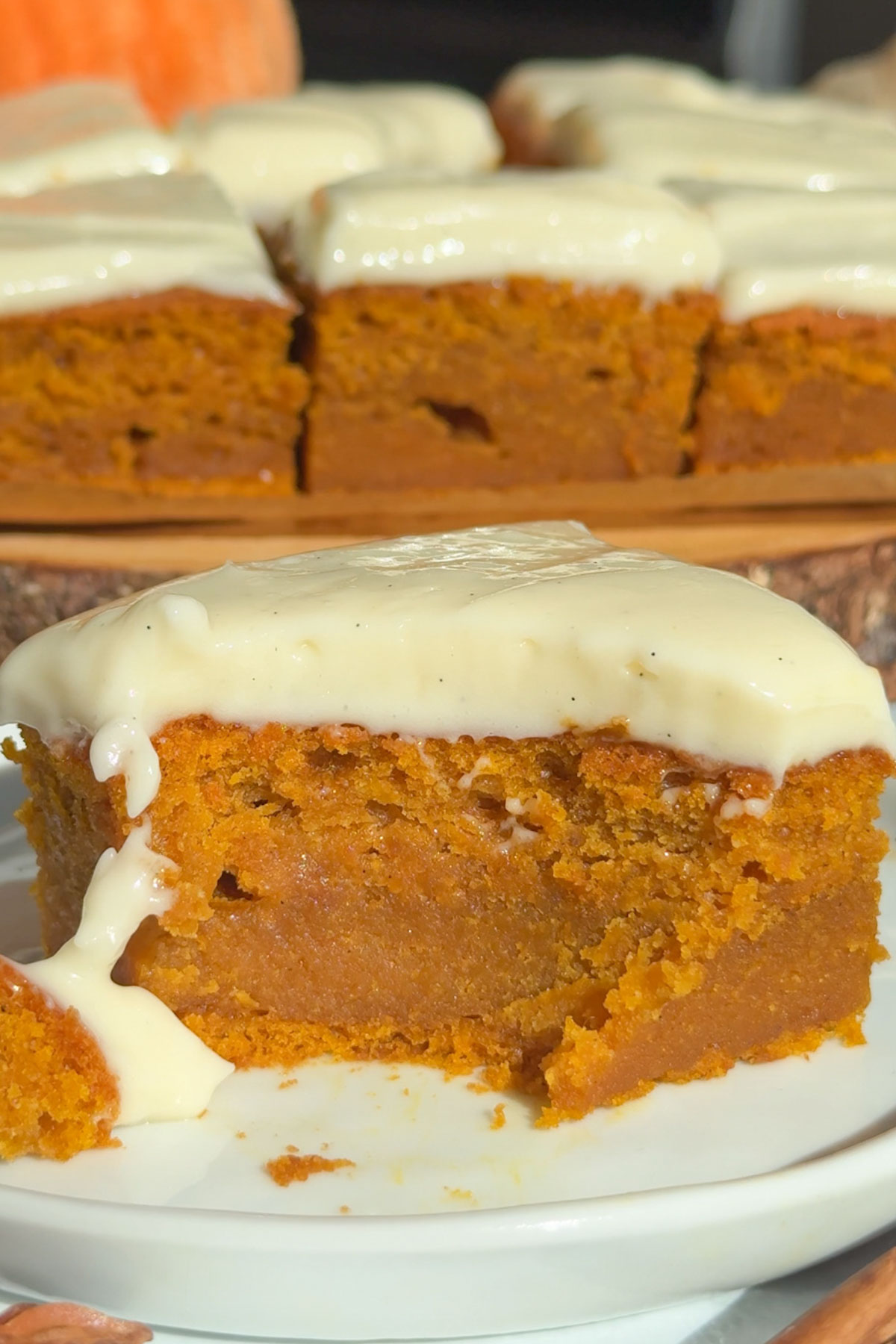 A slice of pumpkin cake with cinnamon cream cheese frosting.