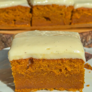 A slice of pumpkin cake with cinnamon cream cheese frosting.