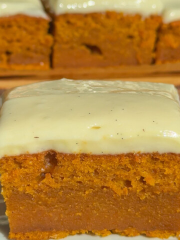 A slice of pumpkin cake with cinnamon cream cheese frosting.