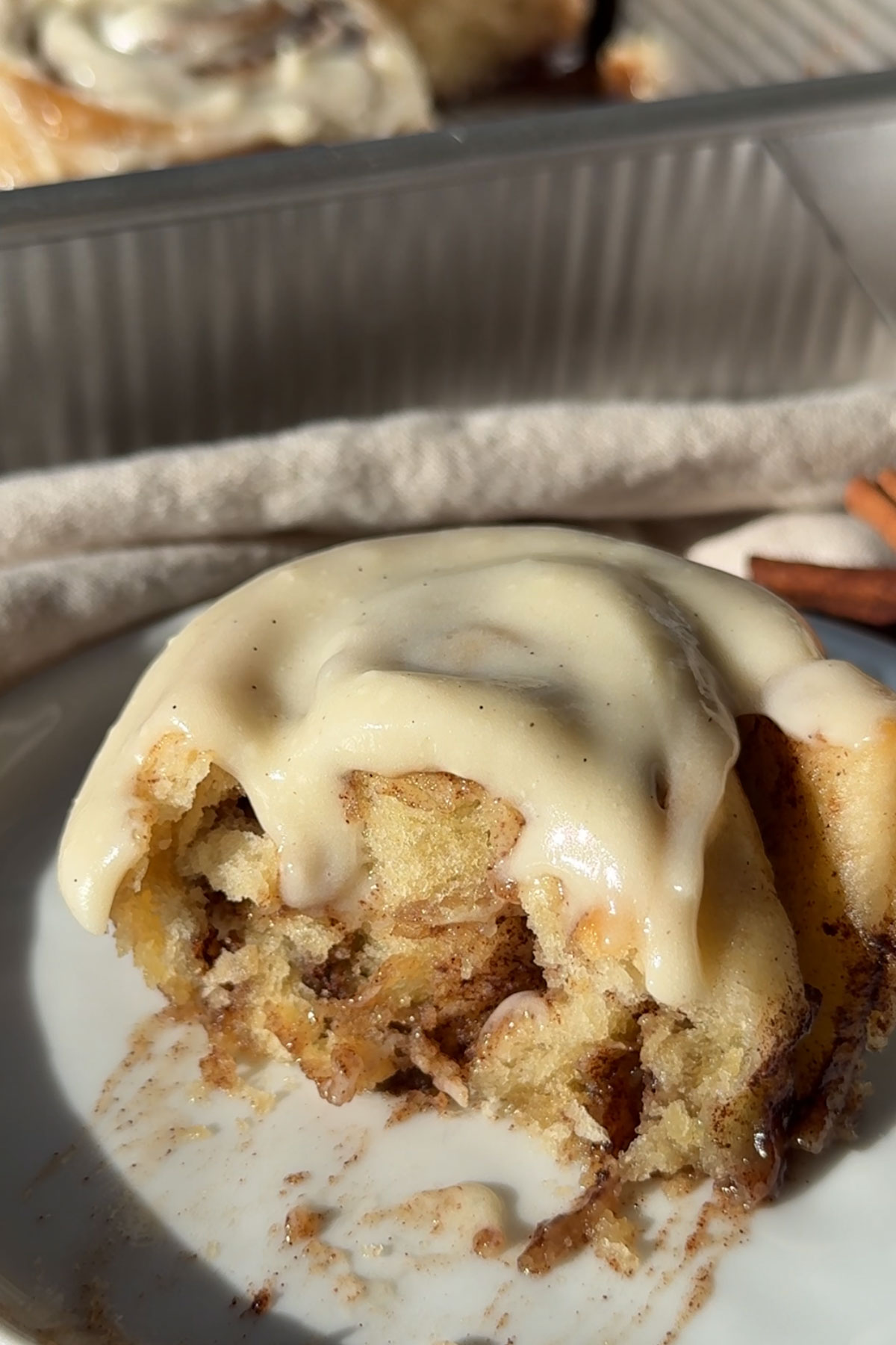 Half of a frosted cinnamon roll on a plate.