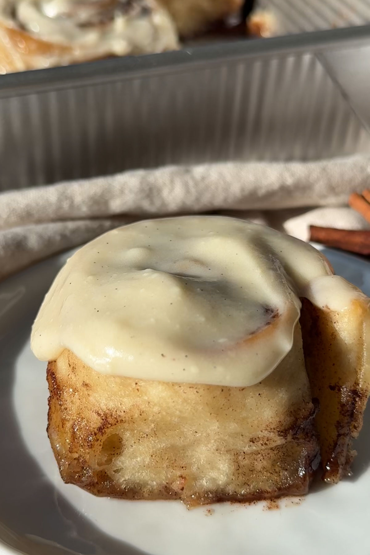 A frosted eggless cinnamon roll on a plate.