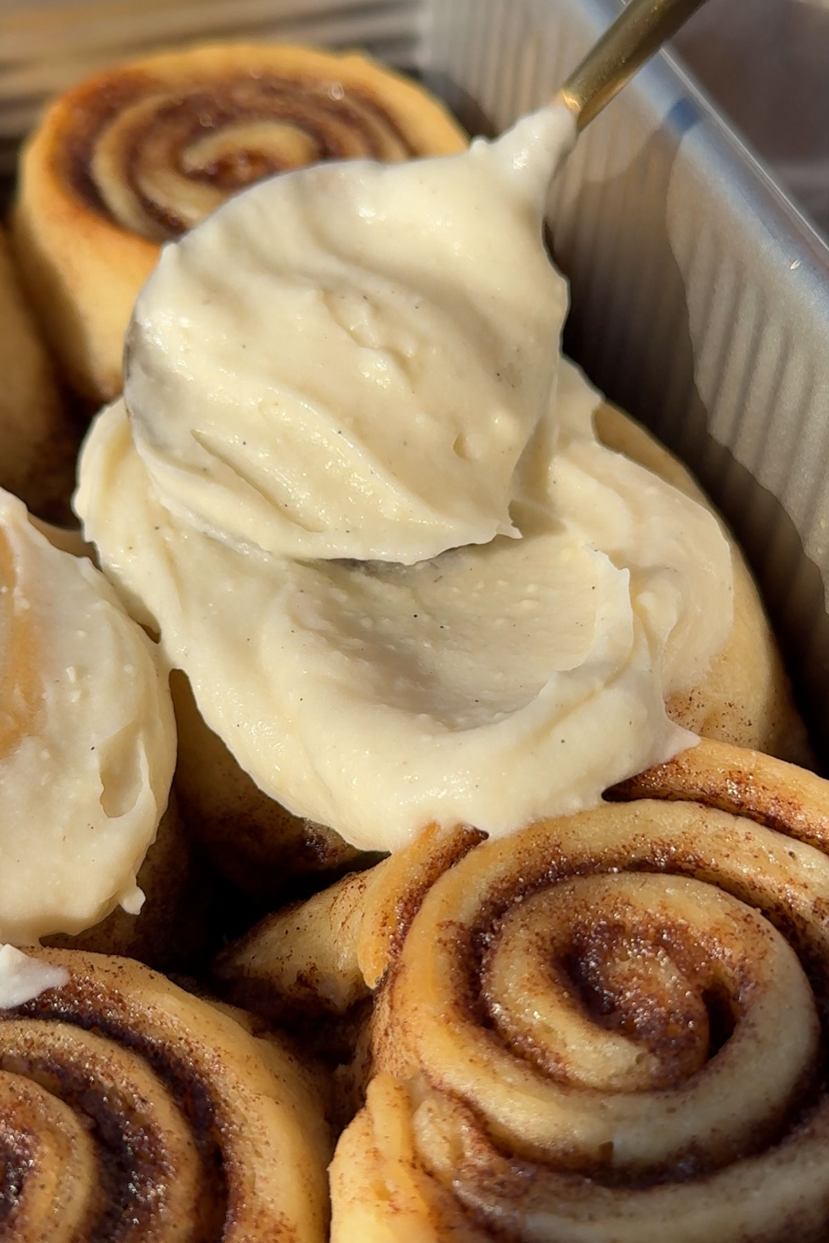 Frosting for cinnamon rolls on a spoon.