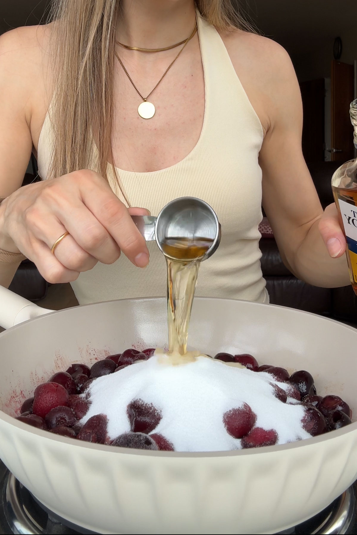 Adding the cherries and sugar to a pot on the stove to make the cherry topping.