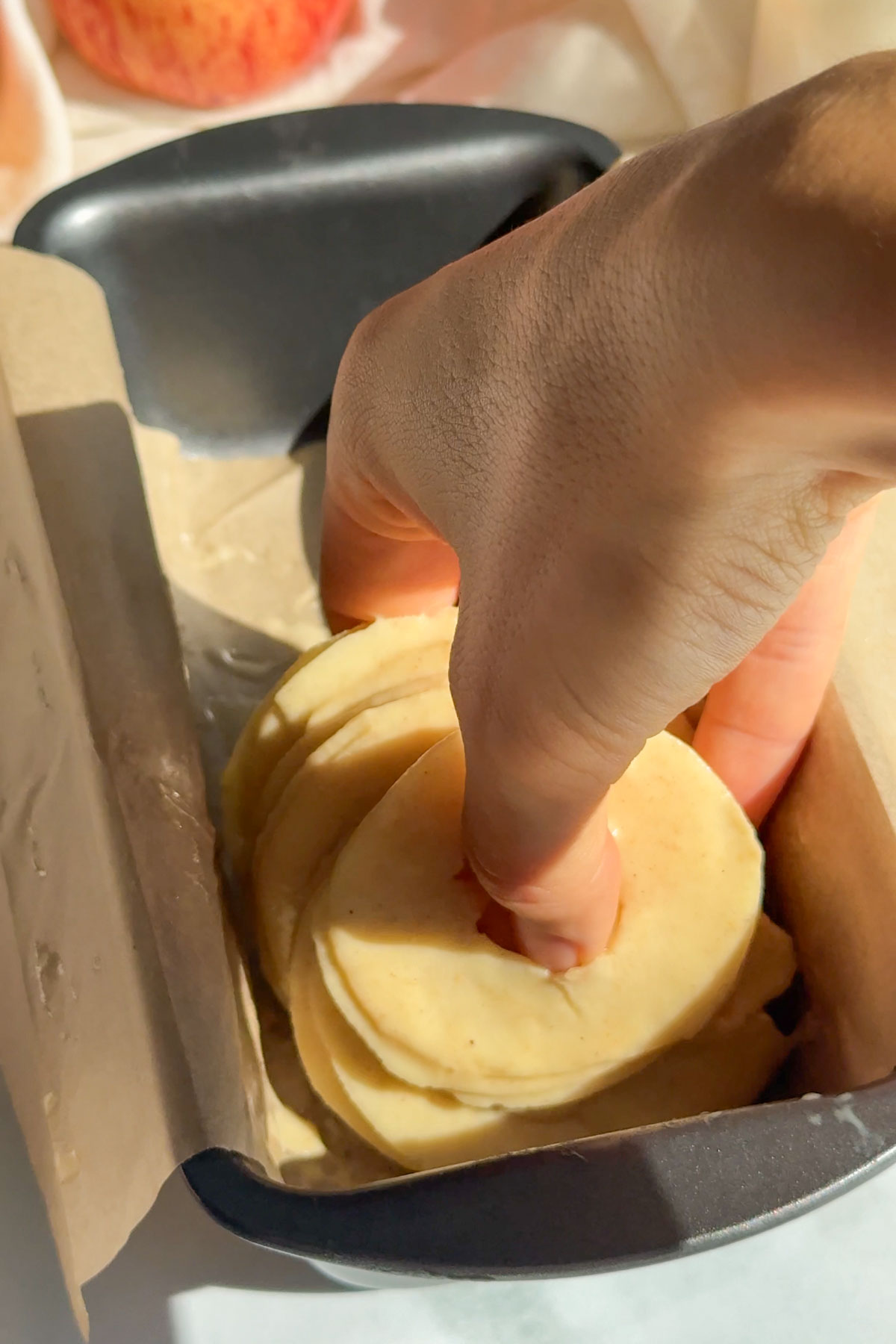 Apples being layered in a loaf pan.