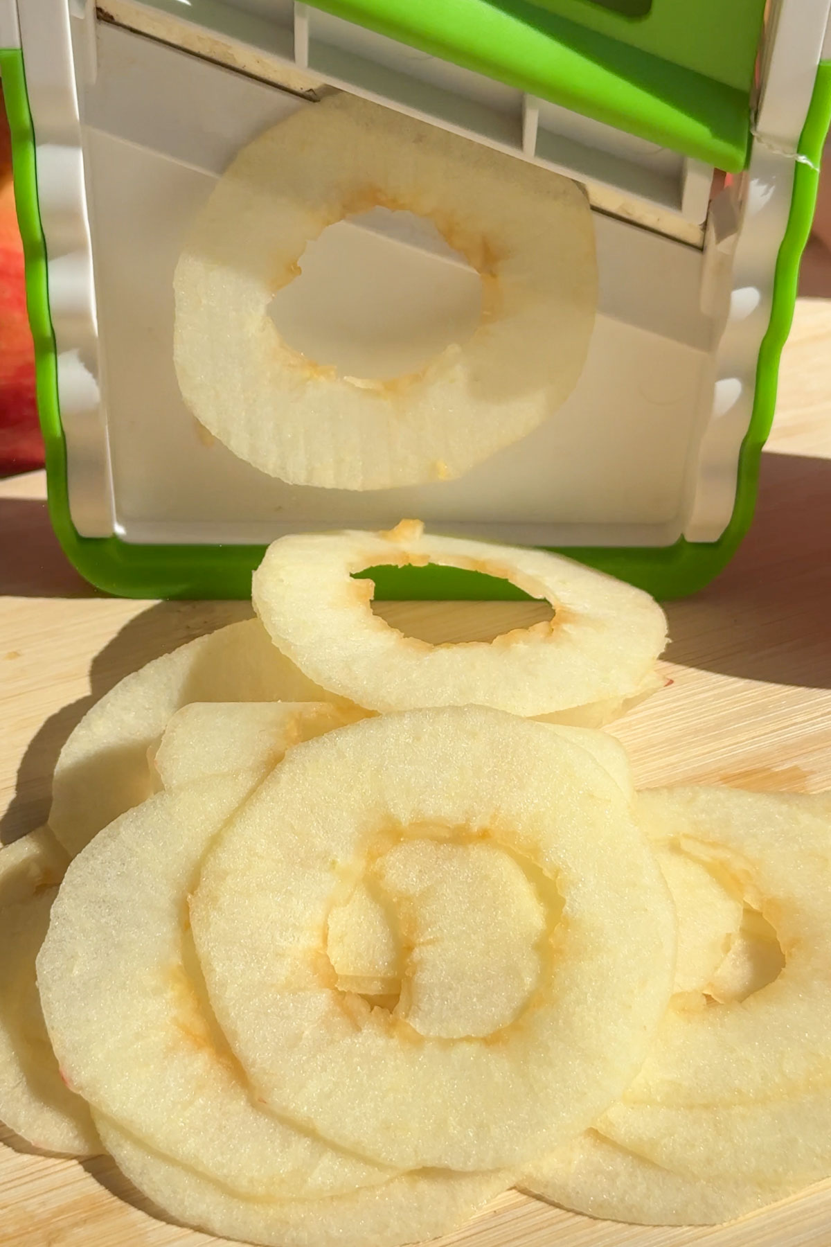 Apples being sliced on a mandolin.