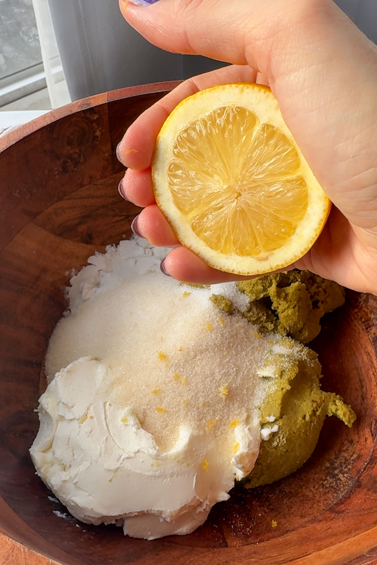 Squeezing a lemon into the pistachio paste and filling ingredients in a large bowl.