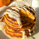 A slice taken out of a stack of pumpkin cinnamon roll pancakes.