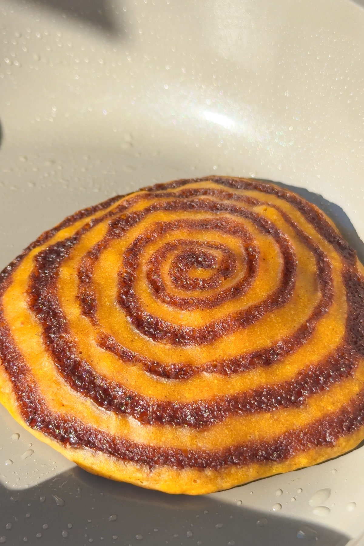 The pumpkin cinnamon roll pancake flipped to cook.