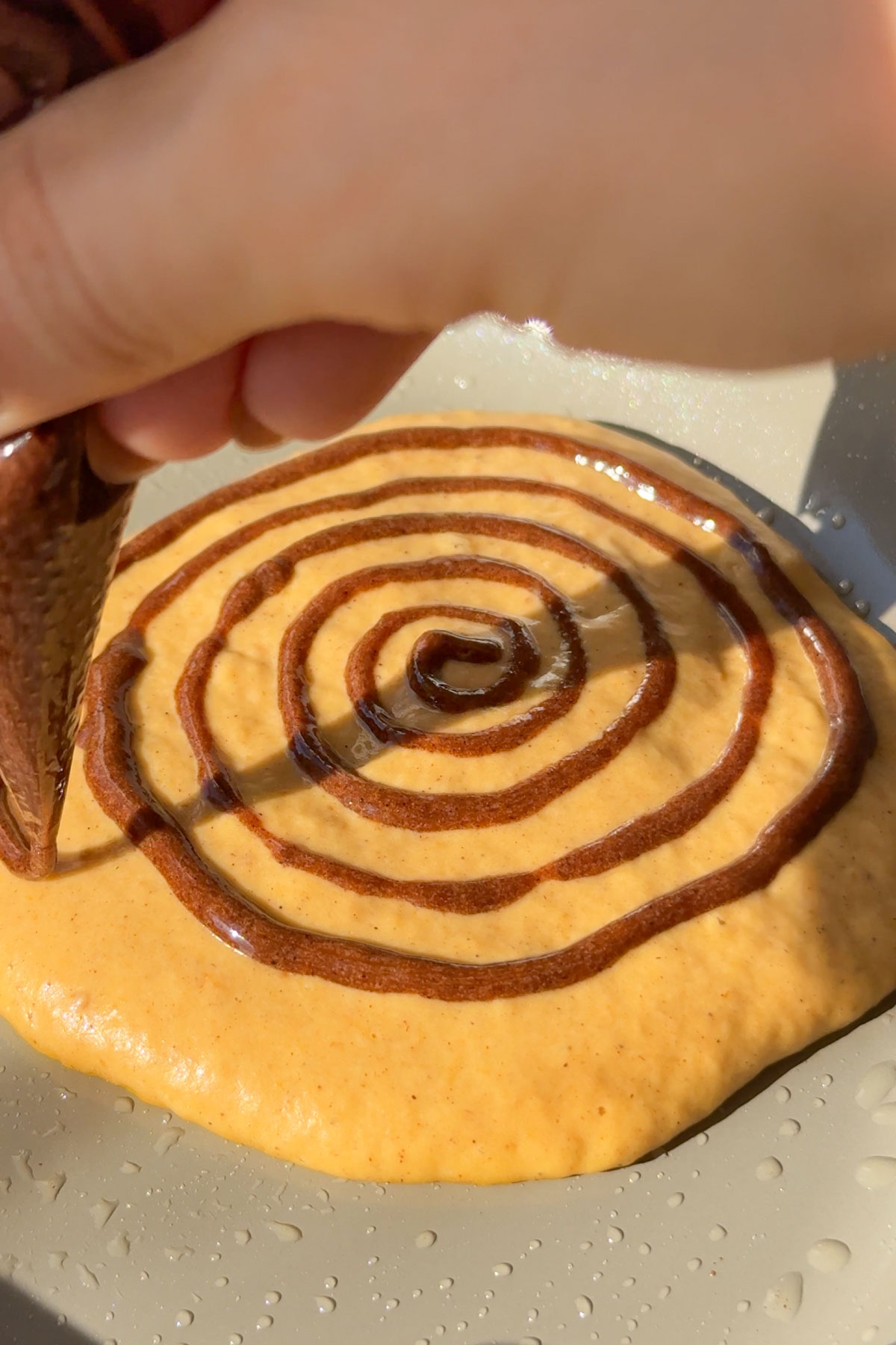 The batter added to the pan and the cinnamon swirled on top.