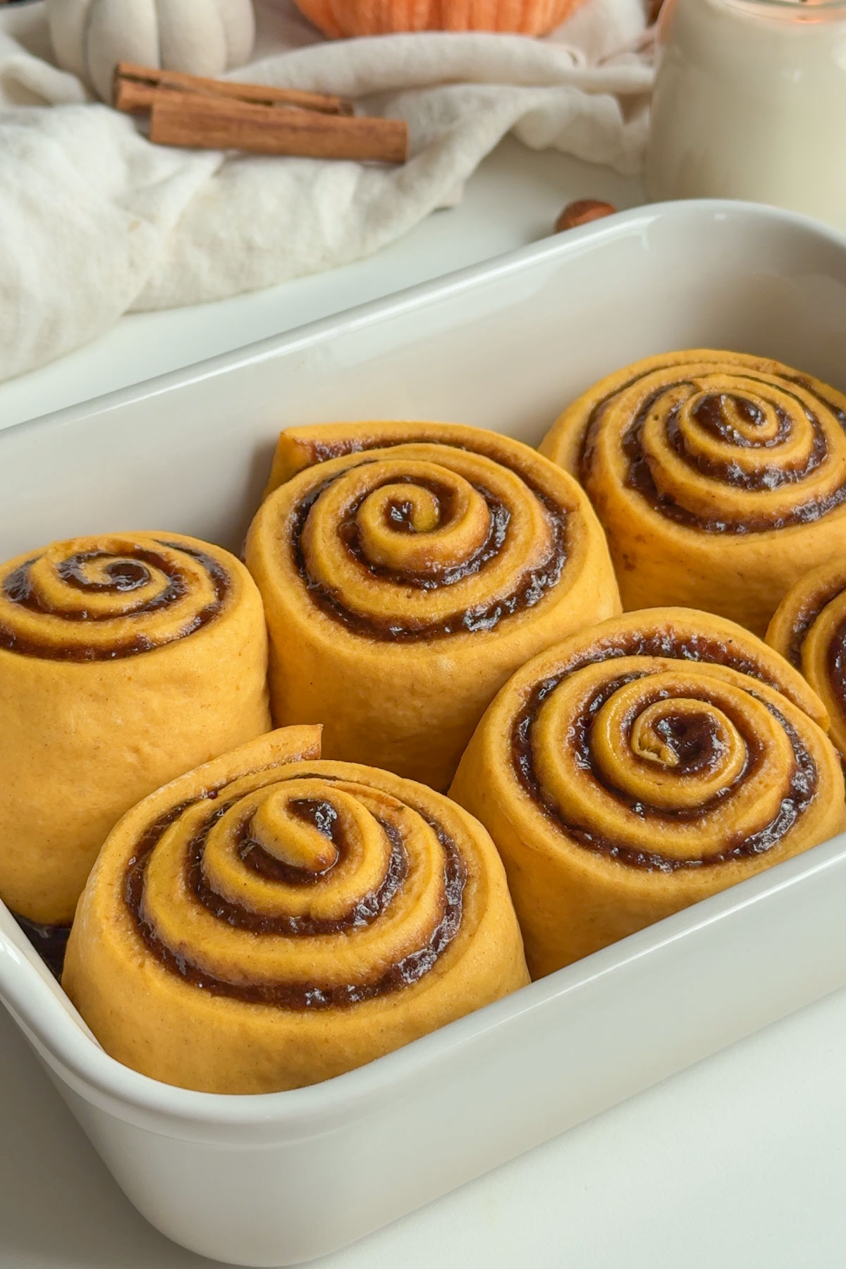 Pumpkin cinnamon rolls in a baking dish after proofing. 