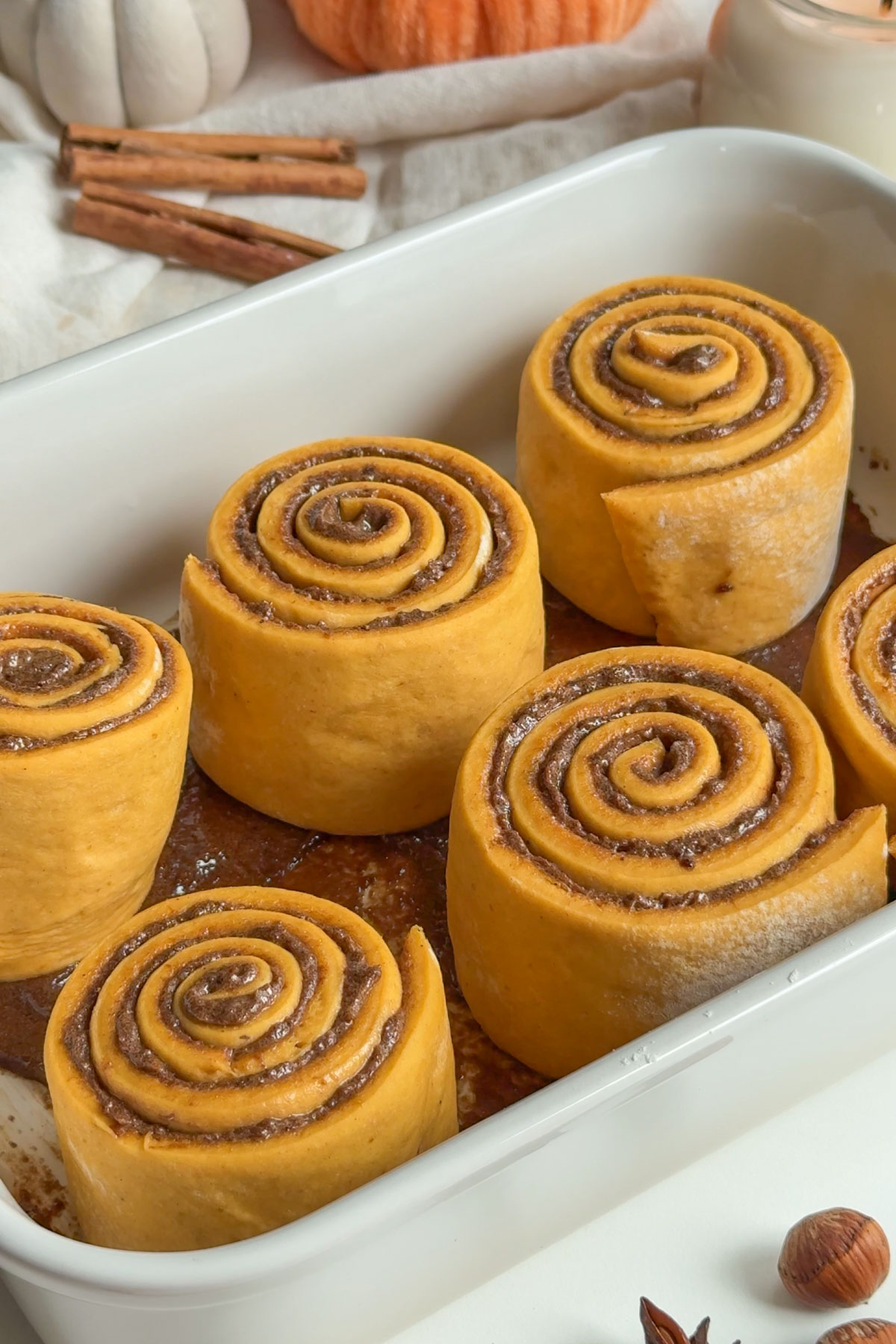 Cut cinnamon rolls with pumpkin in a baking dish. 