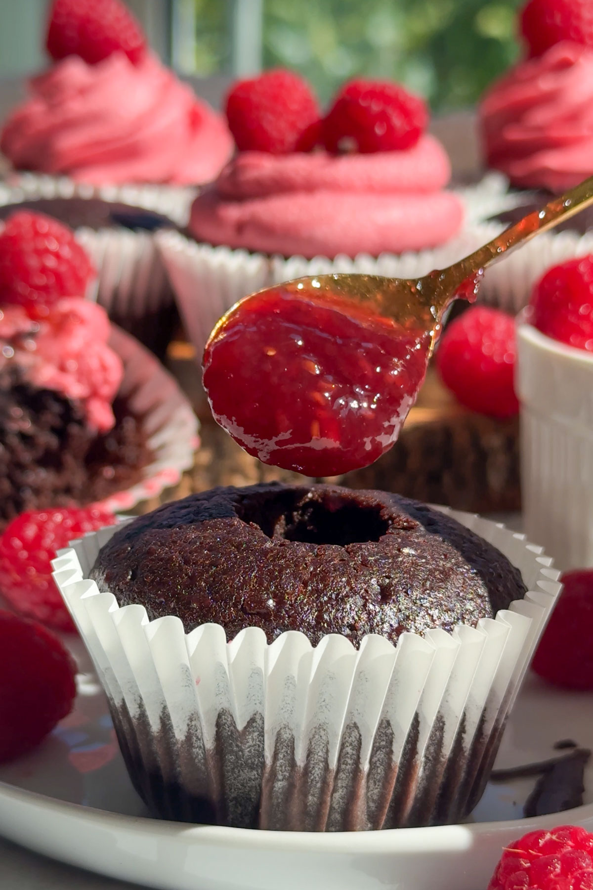 Raspberry filling being put into the chocolate cupcake.