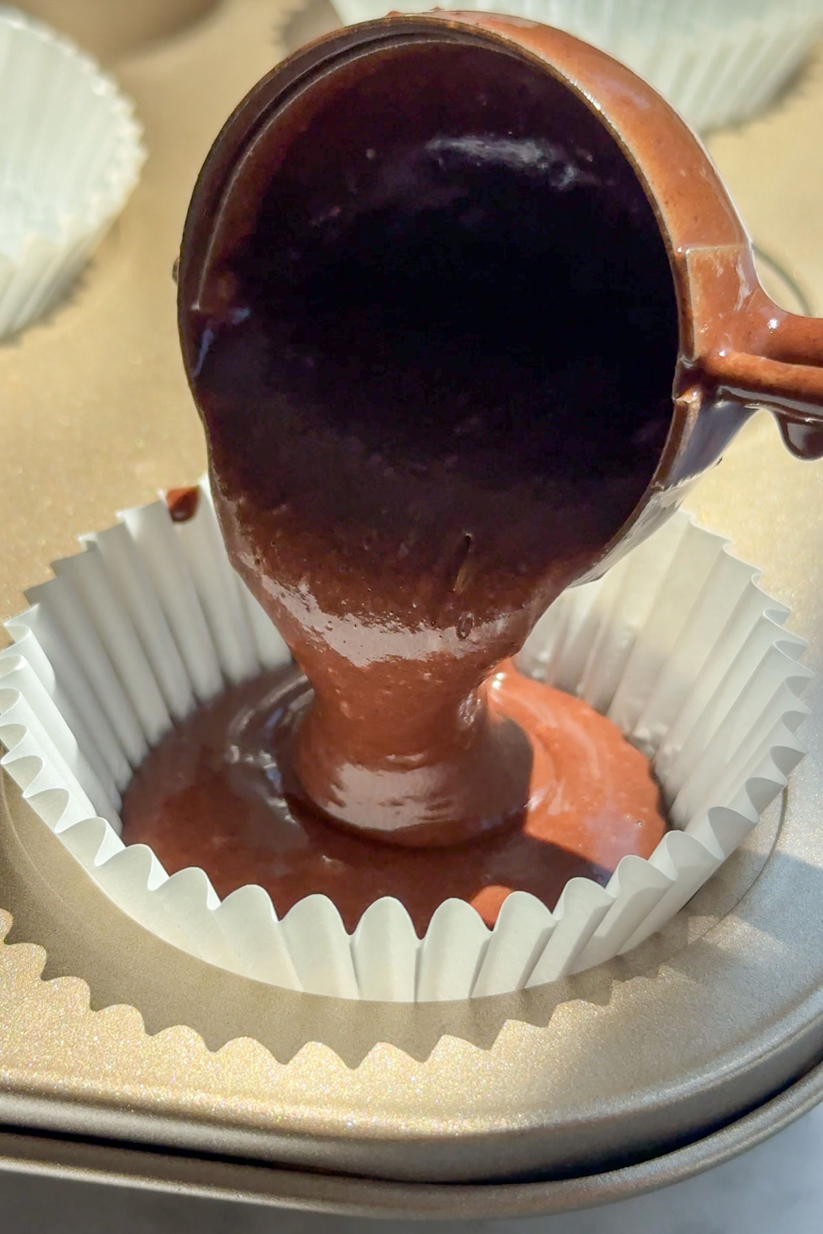 Cupcake batter being poured into the cupcake liner.