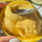 A spoon dipping into some vegan mango ice cream.
