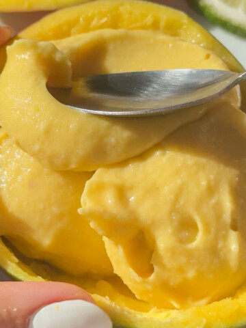 A spoon dipping into some vegan mango ice cream.