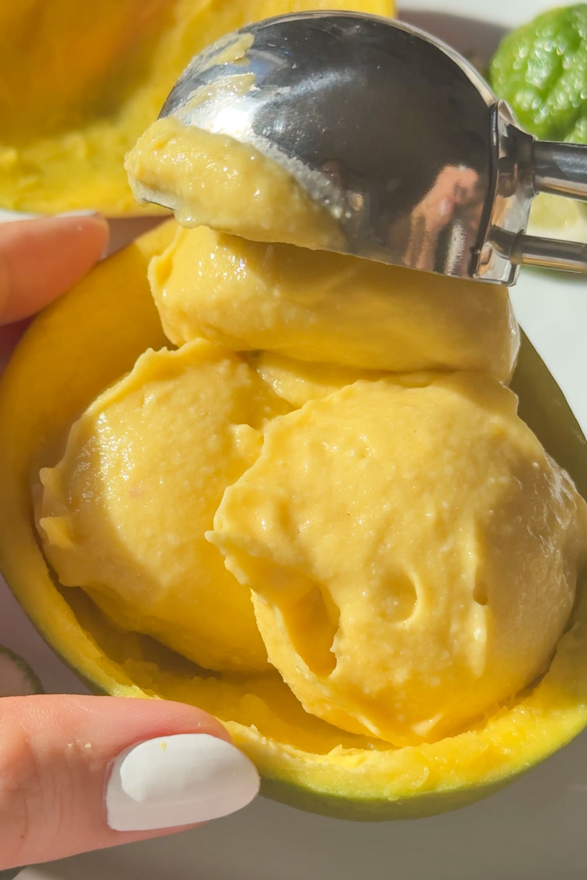 Scooping mango ice cream into the shell of half a mango.