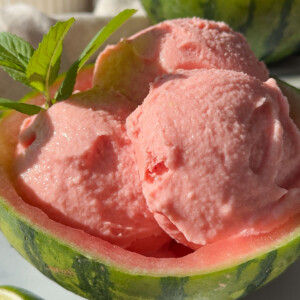 A scooped out watermelon with some watermelon sorbet in it.