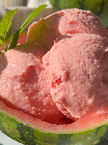 A scooped out watermelon with some watermelon sorbet in it.