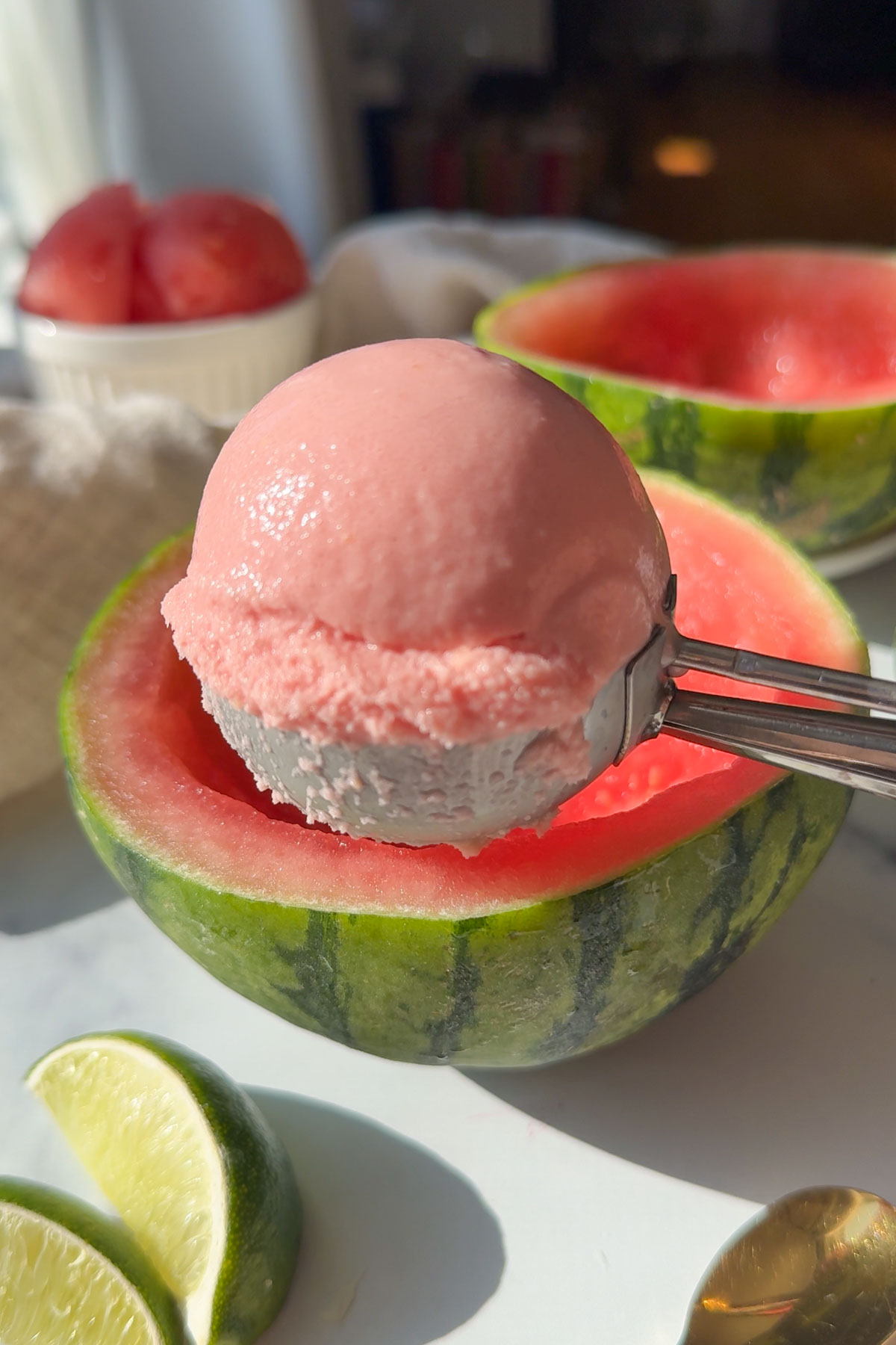 An ice cream scooper holding up some watermelon sorbet in the air.