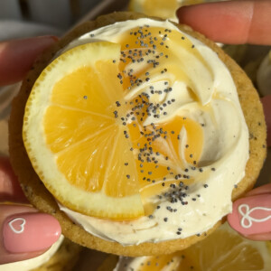 A hand holding up a vegan lemon cookie in the air.
