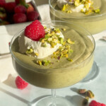 Pistachio chia pudding with whipped topping and a raspberry.