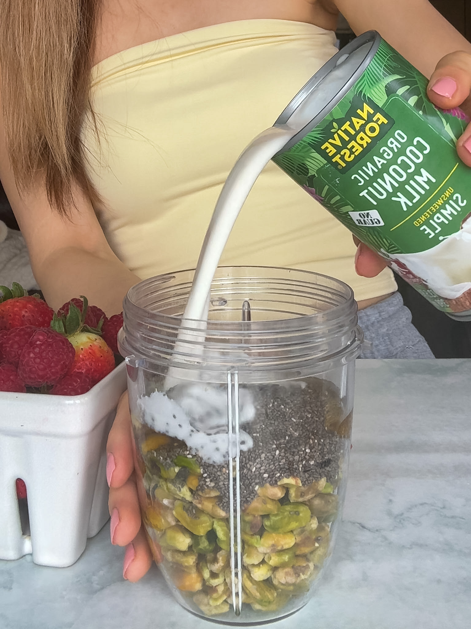Coconut milk being poured into the ingredients for this pudding.